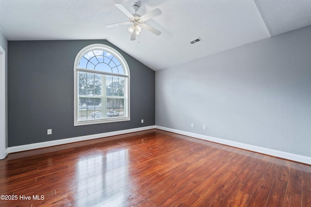 spare room featuring baseboards, visible vents, vaulted ceiling, and wood finished floors