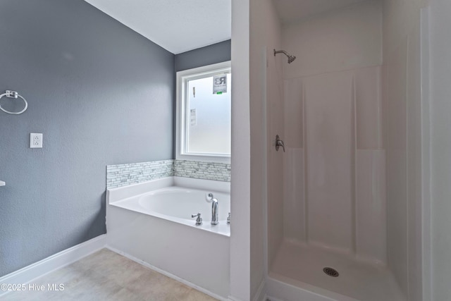 bathroom featuring a stall shower, baseboards, and a garden tub