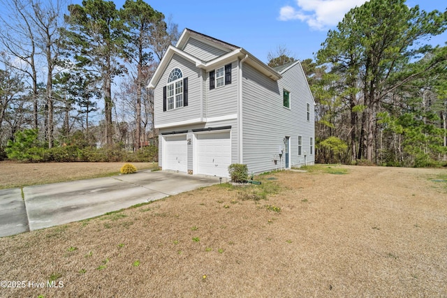 view of side of home featuring a garage, a yard, and driveway