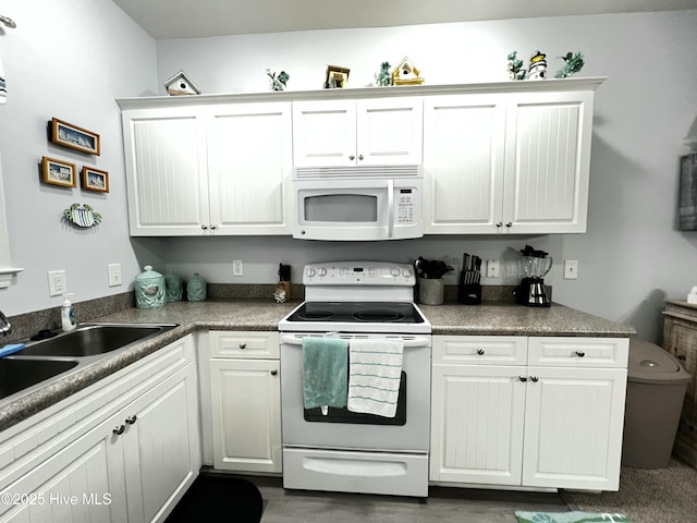 kitchen with dark wood-style flooring, white cabinets, white appliances, and a sink