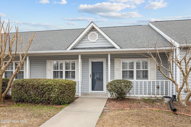 view of front facade with a shingled roof and covered porch