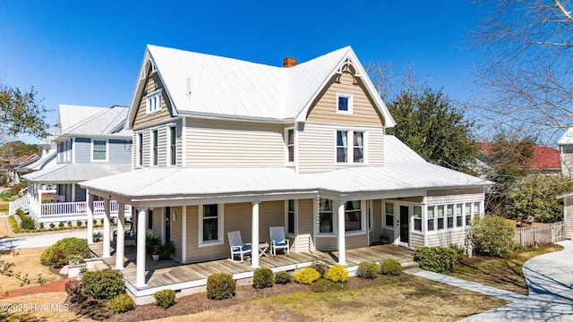 view of front of house featuring a porch, a standing seam roof, metal roof, and a chimney