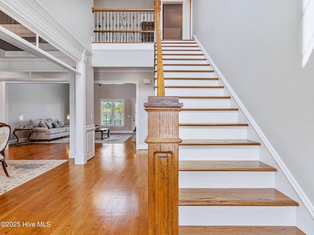 stairway featuring a towering ceiling and wood finished floors