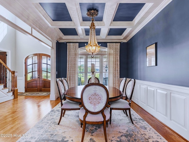 dining space featuring a wainscoted wall, stairs, french doors, an inviting chandelier, and wood finished floors