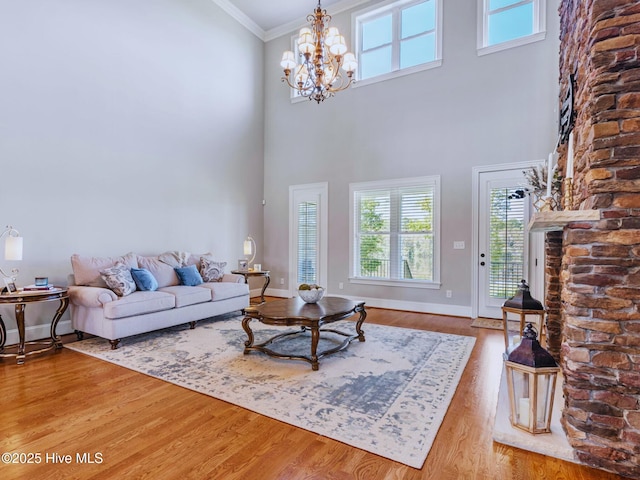 living room with wood finished floors, baseboards, a towering ceiling, crown molding, and a notable chandelier