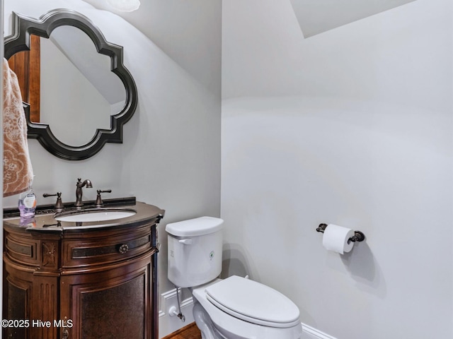 bathroom featuring baseboards, toilet, and vanity