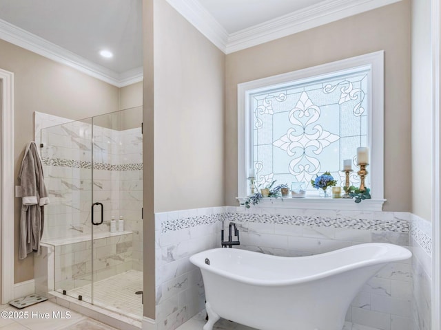 bathroom with crown molding, a freestanding bath, wainscoting, a stall shower, and tile walls