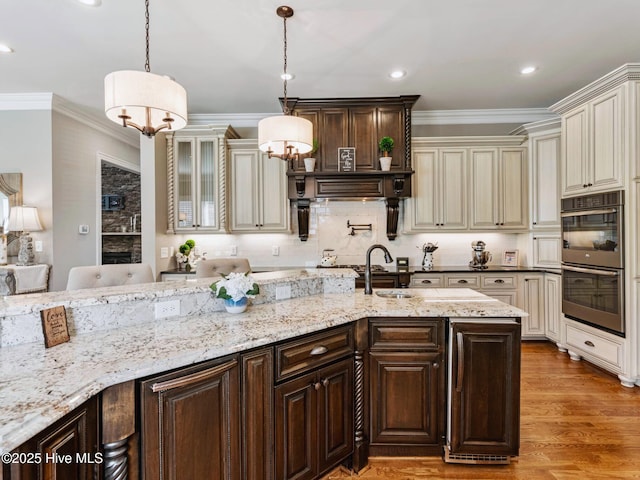 kitchen with stainless steel double oven, cream cabinets, wood finished floors, and crown molding