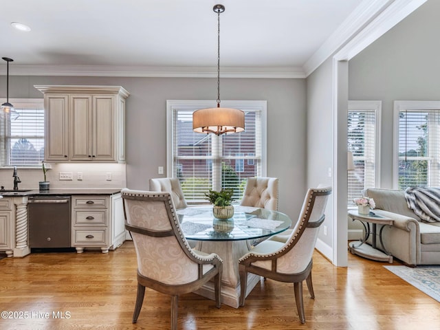 dining area with light wood-style floors, a healthy amount of sunlight, and ornamental molding