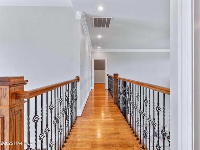 hall featuring visible vents, crown molding, baseboards, recessed lighting, and light wood-style floors