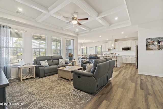 living area featuring plenty of natural light, wood finished floors, visible vents, and coffered ceiling