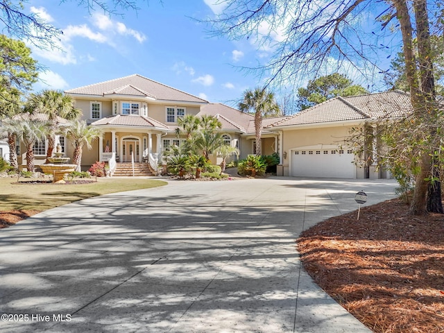 view of front of house featuring a tiled roof, stucco siding, concrete driveway, and a garage