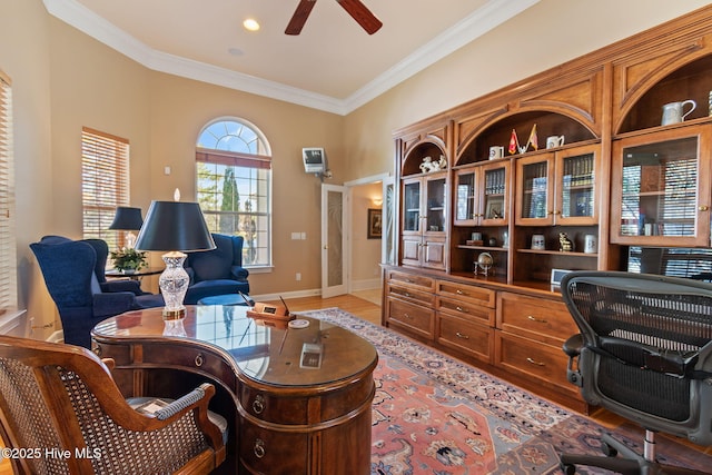 office space featuring a ceiling fan, crown molding, light wood finished floors, and baseboards