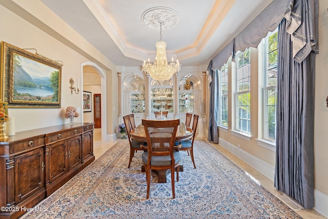 dining area with arched walkways, a chandelier, a tray ceiling, ornamental molding, and baseboards