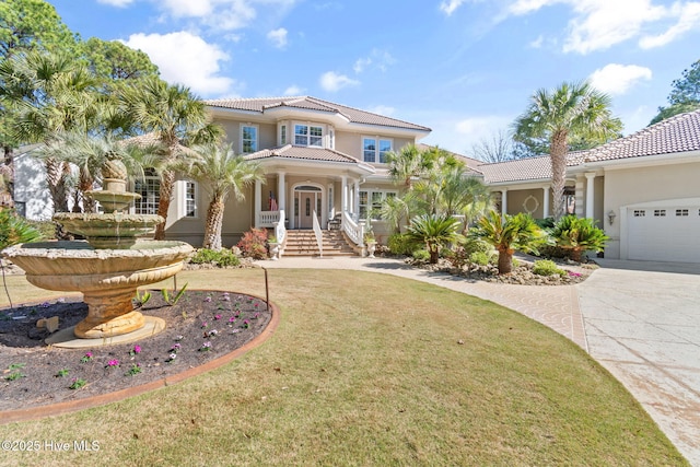 mediterranean / spanish home featuring stucco siding, a tiled roof, a front yard, concrete driveway, and a garage
