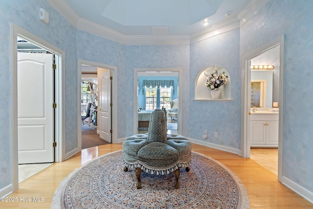 sitting room with plenty of natural light, crown molding, wood finished floors, and baseboards