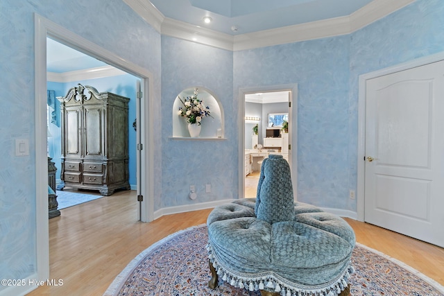 living area with ornamental molding, light wood finished floors, and baseboards