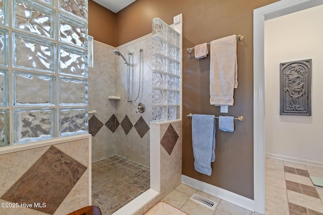 bathroom with a walk in shower, baseboards, and tile patterned floors