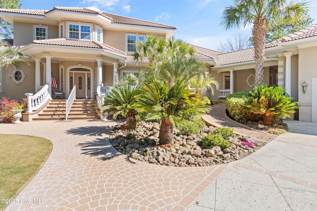 mediterranean / spanish home featuring a tiled roof, stucco siding, and a porch