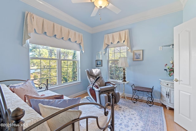 sitting room with a ceiling fan, ornamental molding, baseboards, and light wood-style flooring