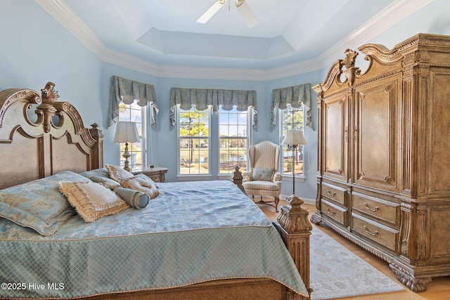 bedroom with a tray ceiling, wood finished floors, a ceiling fan, and crown molding