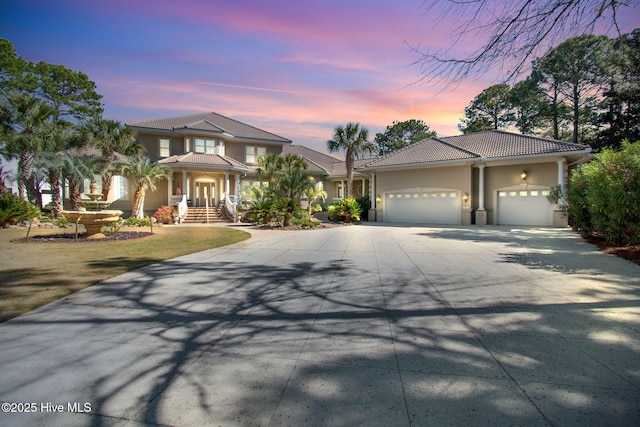 view of front of home with concrete driveway, stucco siding, a garage, and a tile roof