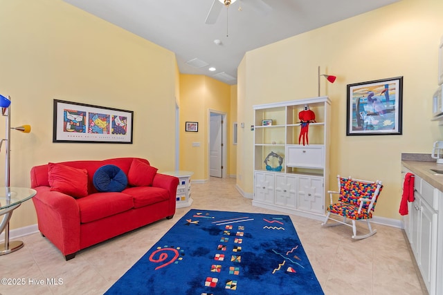 living area featuring a ceiling fan, light tile patterned floors, and baseboards