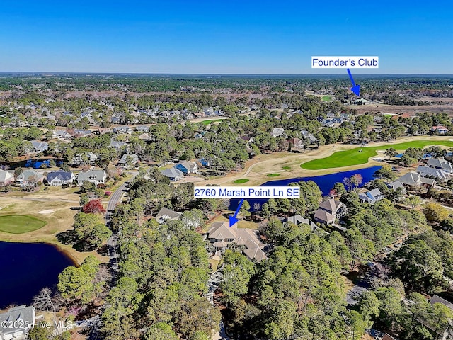 aerial overview of property's location featuring a golf club, nearby suburban area, a nearby body of water, and a tree filled landscape