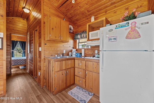 kitchen featuring white appliances, under cabinet range hood, a wealth of natural light, and a sink