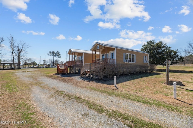 manufactured / mobile home featuring stairway, a wooden deck, gravel driveway, and a front lawn