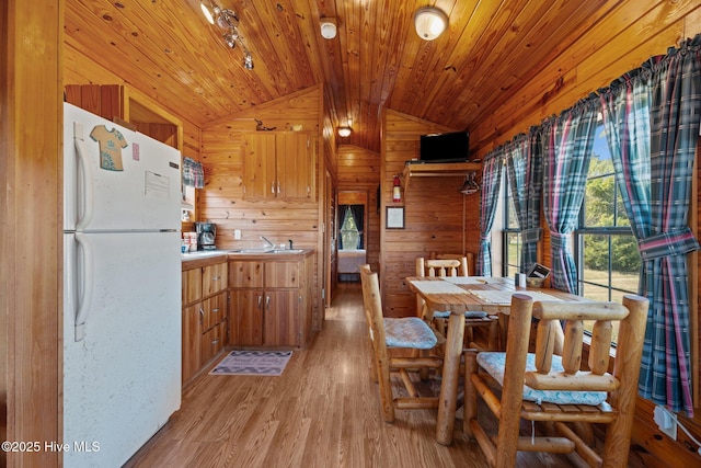 dining area with light wood-type flooring, wooden walls, wood ceiling, and vaulted ceiling