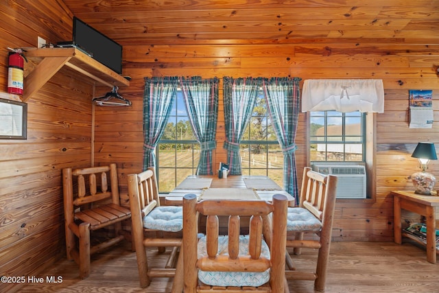 dining area featuring wood walls, cooling unit, and wood finished floors