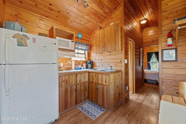 kitchen featuring white appliances, wood ceiling, wood walls, and a sink