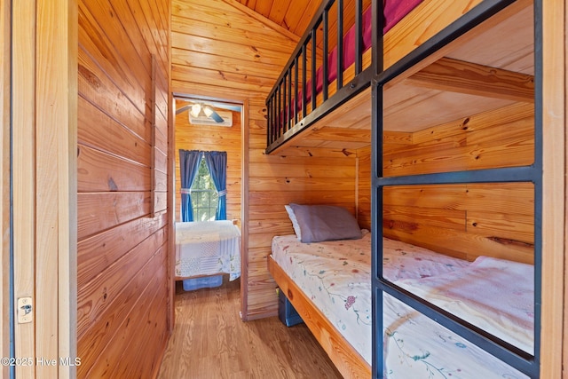 unfurnished bedroom with lofted ceiling, wood finished floors, wood ceiling, and wood walls