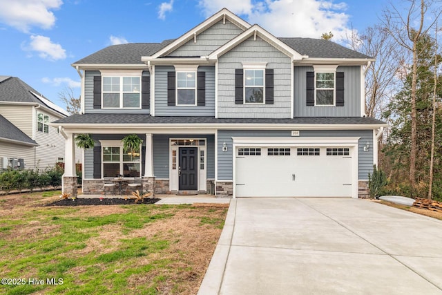 craftsman-style house with concrete driveway, stone siding, an attached garage, covered porch, and a front yard