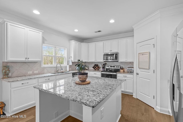 kitchen featuring wood finished floors, a sink, visible vents, white cabinetry, and appliances with stainless steel finishes