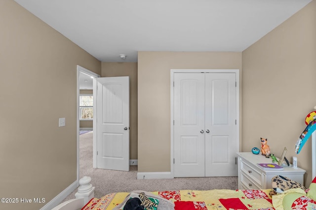 bedroom featuring light carpet, a closet, and baseboards