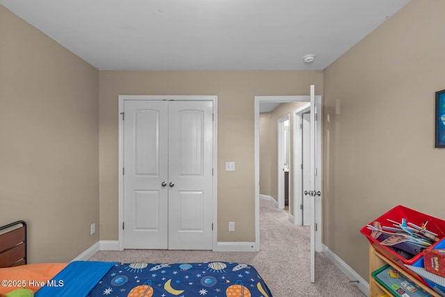 carpeted bedroom featuring a closet and baseboards