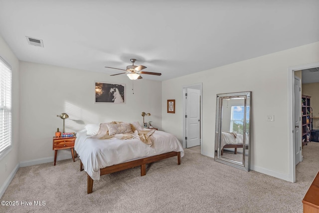 bedroom featuring light carpet, multiple windows, visible vents, and baseboards