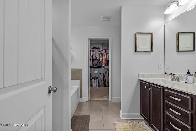 full bath featuring baseboards, tile patterned floors, a garden tub, a walk in closet, and vanity