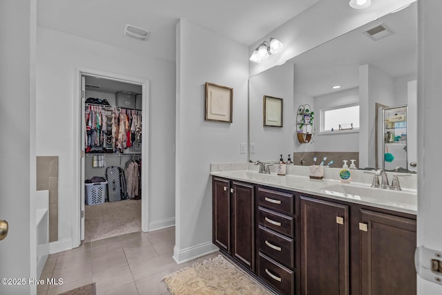 full bath with double vanity, visible vents, tile patterned floors, a walk in closet, and a sink