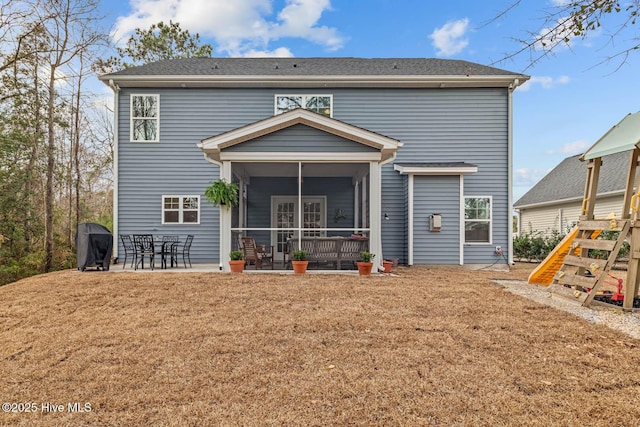 back of property with a sunroom, a lawn, and a patio