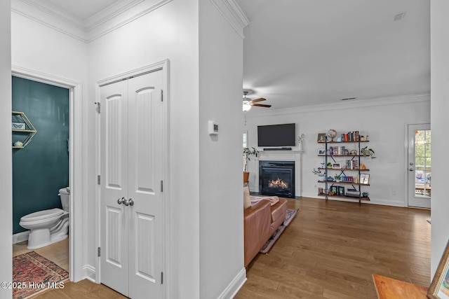 hallway with crown molding, baseboards, and wood finished floors