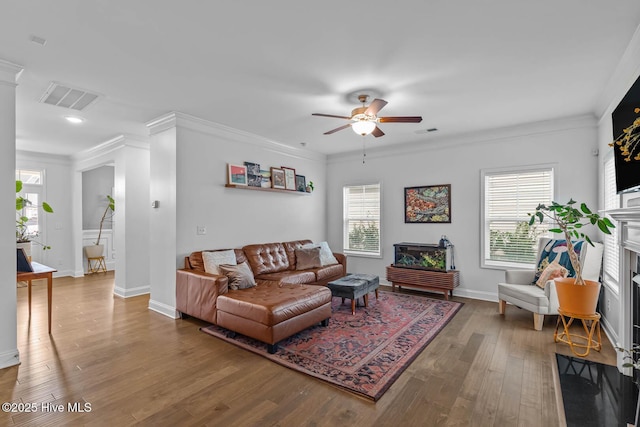 living area with ornamental molding, a fireplace, wood finished floors, and visible vents