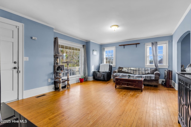 living room with baseboards, visible vents, arched walkways, wood-type flooring, and crown molding