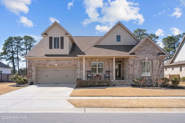 view of front facade with fence, driveway, a porch, a shingled roof, and brick siding