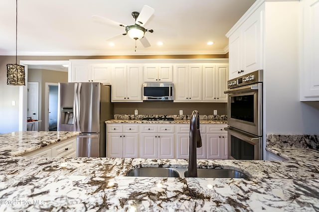 kitchen with white cabinets, a ceiling fan, appliances with stainless steel finishes, light stone counters, and a sink