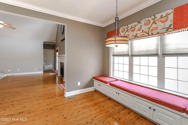 interior space featuring a fireplace, visible vents, baseboards, light wood finished floors, and crown molding