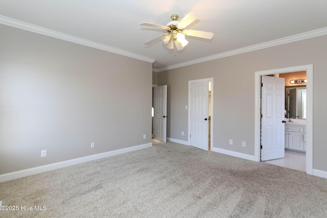 unfurnished bedroom with baseboards, light colored carpet, ensuite bath, ceiling fan, and ornamental molding