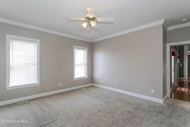 carpeted spare room featuring baseboards, ceiling fan, visible vents, and crown molding